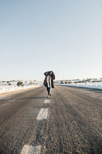 Mid adult woman standing on empty road during winter