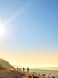 People walking on beach against clear sky