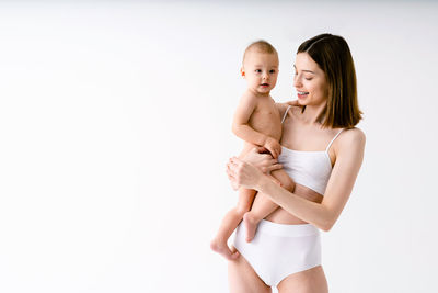 Portrait of young woman standing against white background