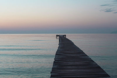 Pier over sea against sky during sunset