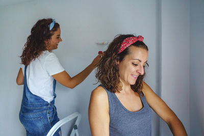 Cheerful women painting wall at home