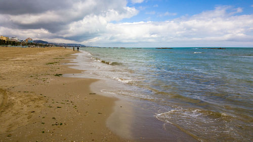 Scenic view of beach against cloudy sky