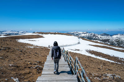 Rear view of man walking on snow covered mountain