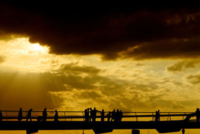 Silhouette people by sea against sky during sunset