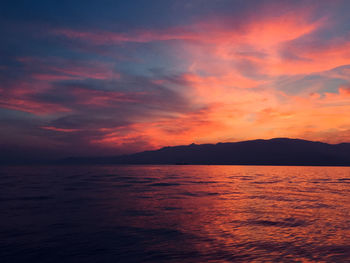 Scenic view of sea against dramatic sky during sunset