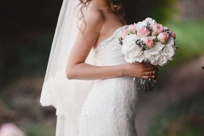 Midsection of bride holding bouquet