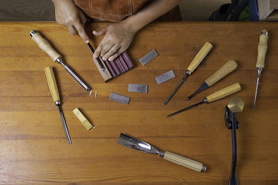Craftswoman sharpens a tool with an stone