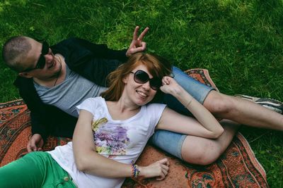 Portrait of happy young couple relaxing on field at park