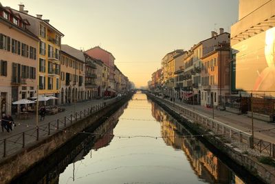 Reflection of buildings in city against clear sky