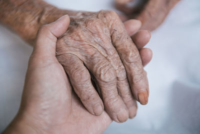 Cropped image of people holding hands at home