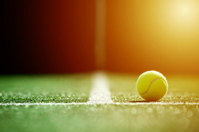 Close-up of tennis ball on field in court during sunset