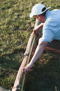 Man measuring wood with tape measure at field 