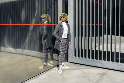 Man standing by glass wall in city