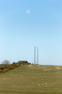 Communications towers on field against clear sky