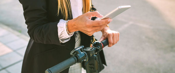 Midsection of woman using smart phone standing outdoors