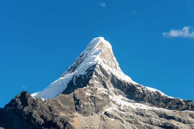 Low angle view of snowcapped mountain against clear blue sky