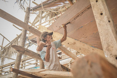 Low angle view of woman standing on wood against trees