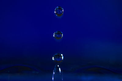 Close-up of bubbles over water against blue background