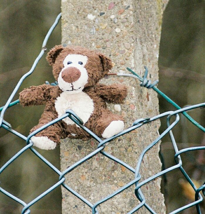 CLOSE-UP OF STUFFED TOY HANGING FROM METAL