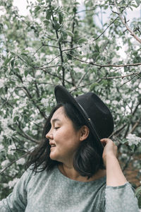 Beautiful asian plus size model wearing green dress enjoying smell of blooming spring tree outdoor