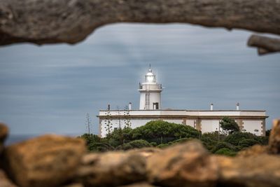 Lighthouse by building against sky