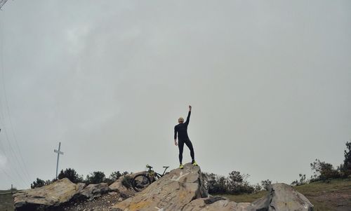 Woman standing on rock against sky