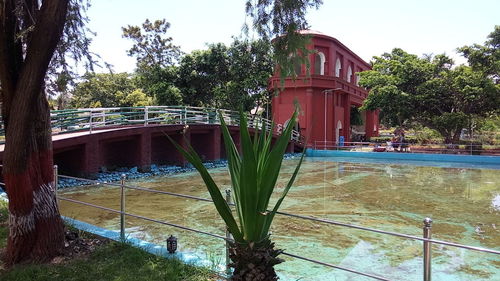 Bridge over pond by building against sky