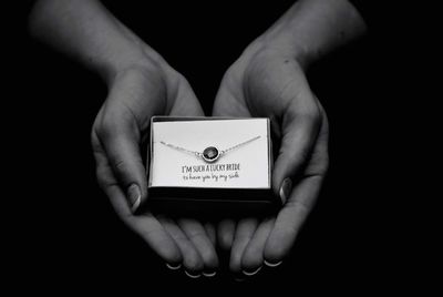 Close-up of hands holding jewelry against black background