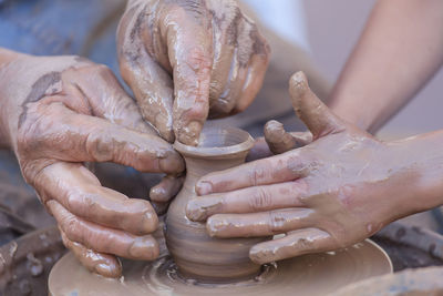 Cropped image of people making mud pots
