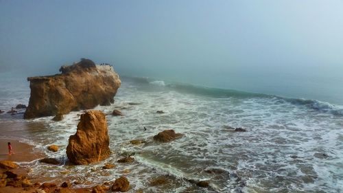 High angle view of rock formations in sea against sky during foggy weather