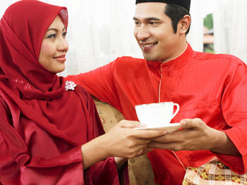 Couple in traditional clothing having coffee on sofa at home