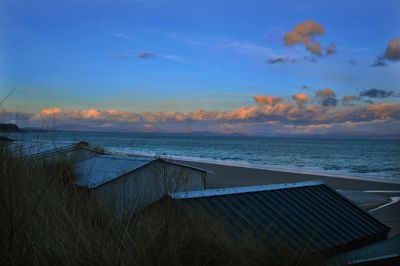 Huts at beach against sky during sunset
