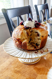 Panettone bread with cherries and whipped cream on a holiday table at christmas.