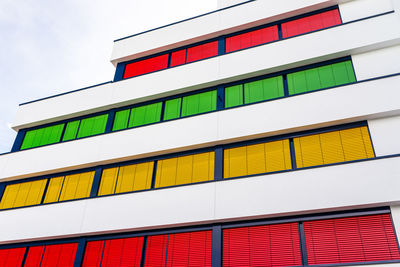 Elevation of a modern office building with different colors of blinds on each floor.