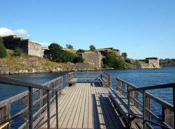 View of building by river against clear blue sky