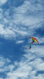 Low angle view of colorful kite flying against cloudy sky