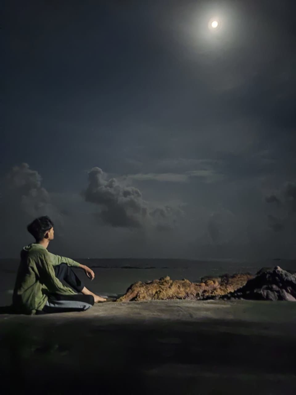 moon, sky, night, one person, darkness, full moon, cloud, moonlight, light, nature, sitting, water, horizon, beach, sea, adult, beauty in nature, land, men, morning, side view, tranquility, young adult, person, scenics - nature, ocean, outdoors, looking, full length, leisure activity, relaxation, copy space, solitude