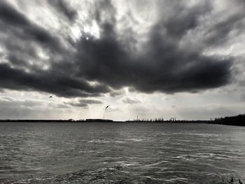 Seagull flying over sea against cloudy sky