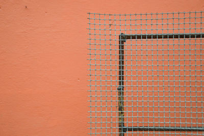 Full frame shot mesh wire against a pink wall