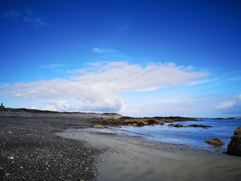 Scenic view of beach against blue sky