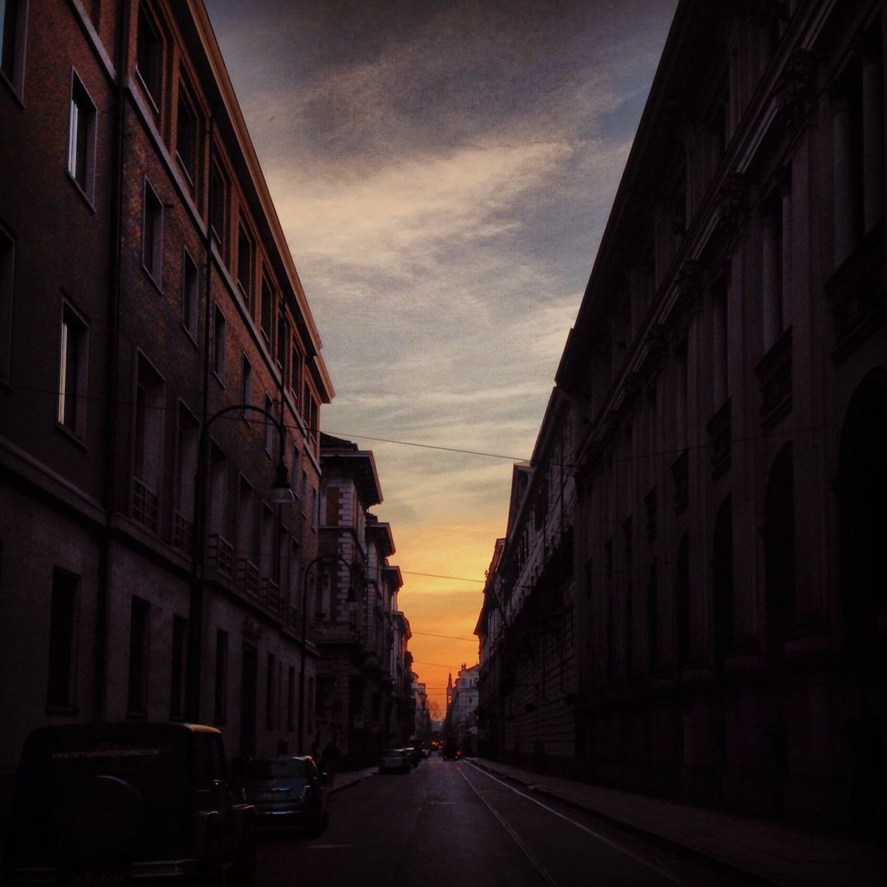 architecture, building exterior, built structure, transportation, car, sky, street, land vehicle, the way forward, city, mode of transport, diminishing perspective, road, cloud - sky, building, residential building, residential structure, vanishing point, cloud, cloudy