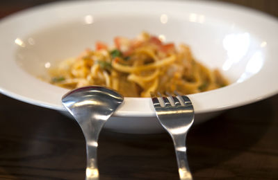 Close-up of silverware on bowl with spaghetti at table