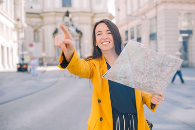 Portrait of young woman holding umbrella while standing in city