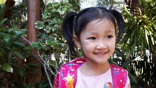 Cute smiling girl looking away while standing outdoors