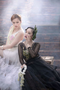 Young women sitting against wall