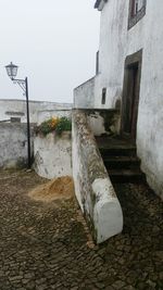 Footpath by building against clear sky
