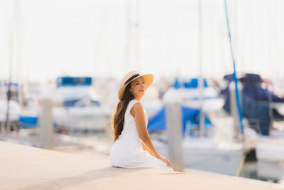 Beautiful young woman sitting at harbor