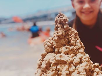 Close-up of man holding sunglasses at beach against sky