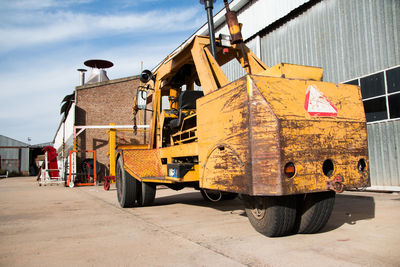 Yellow crane on road in city against sky