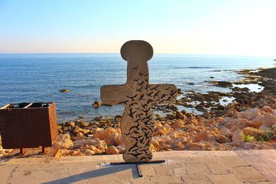 Stone wall by sea against clear sky